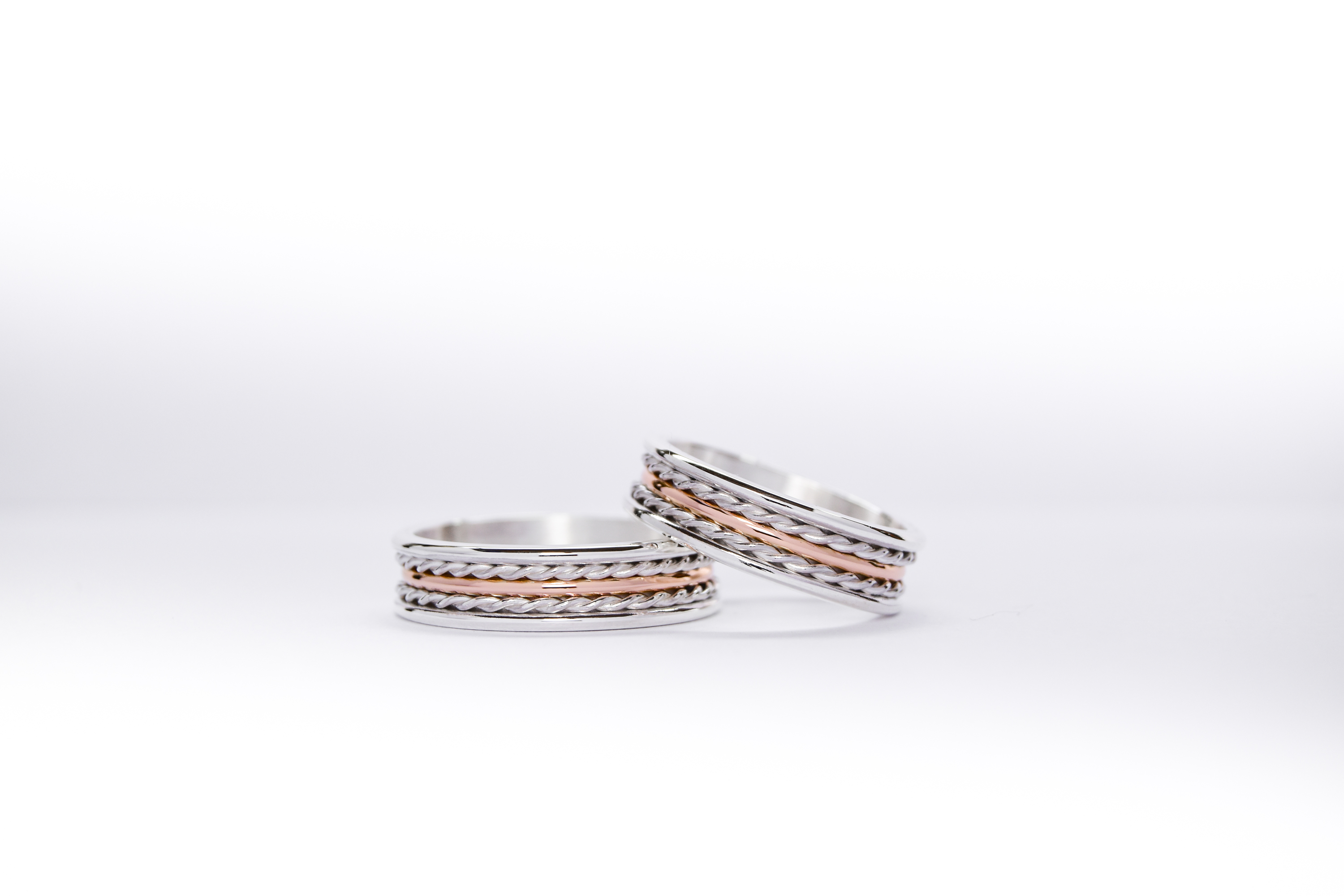 Alianzas de plata y oro 18k rosa con trenzas sobre fondo blanco