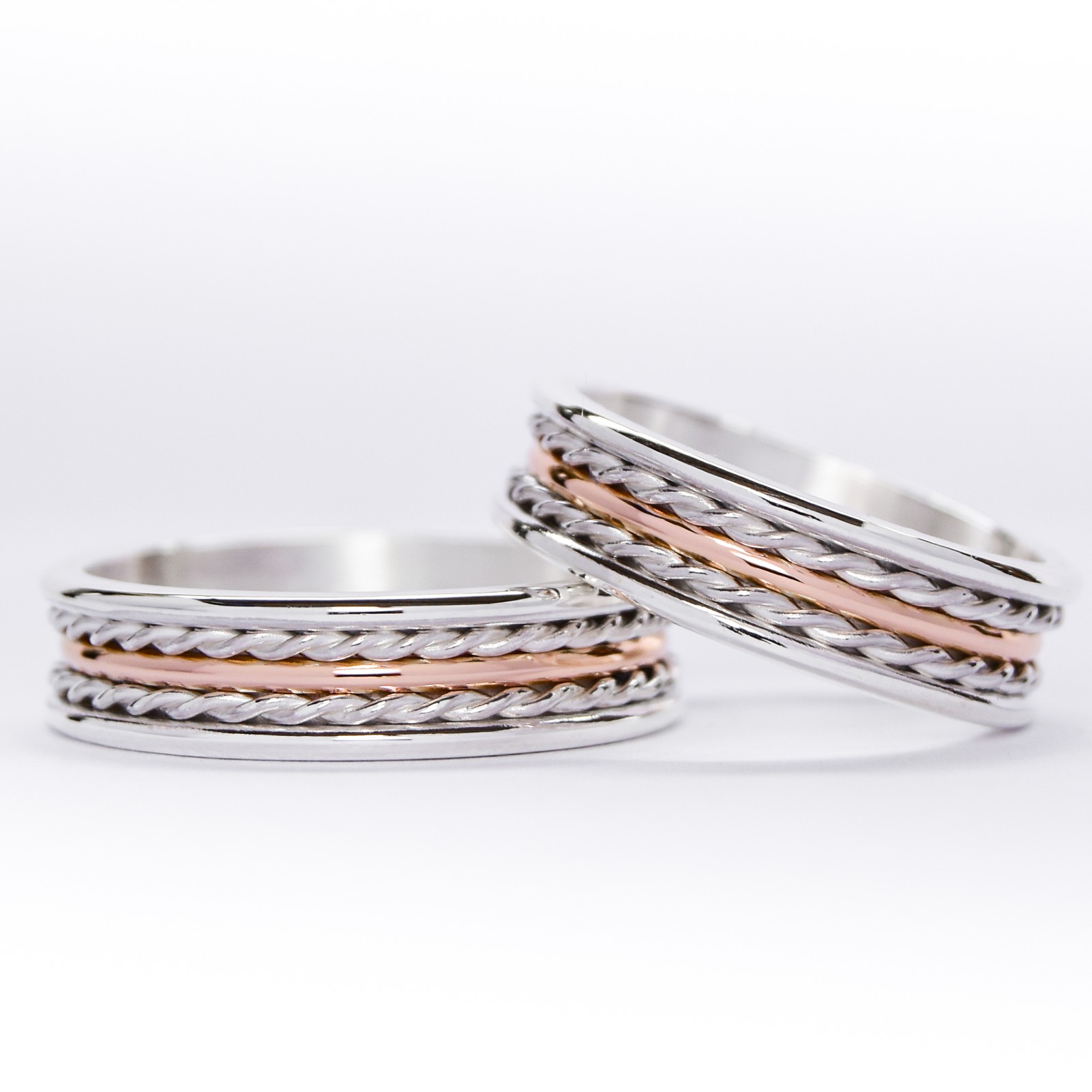 Alianzas de plata y oro 18k rosa con trenzas sobre fondo blanco