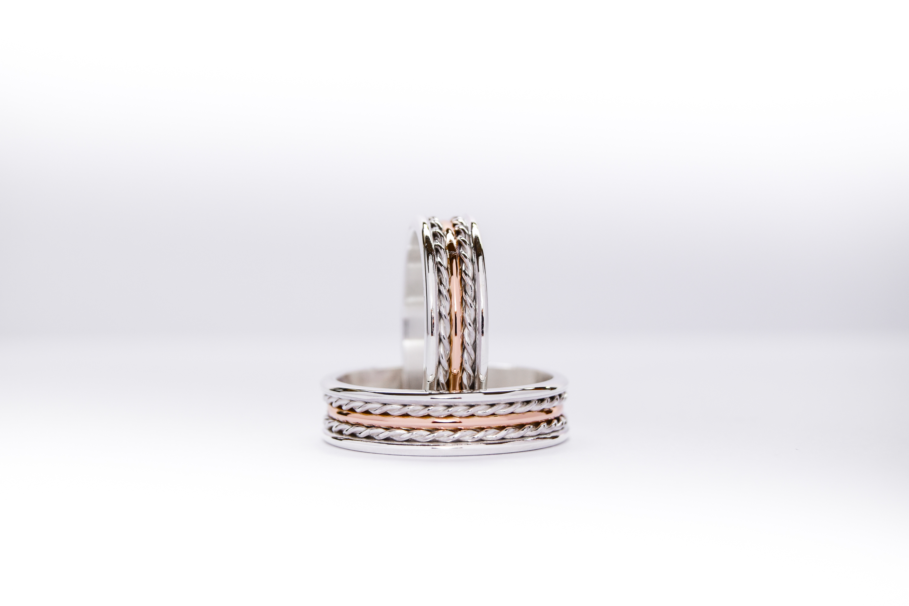 Alianzas de plata y oro 18k rosa con trenzas sobre fondo blanco