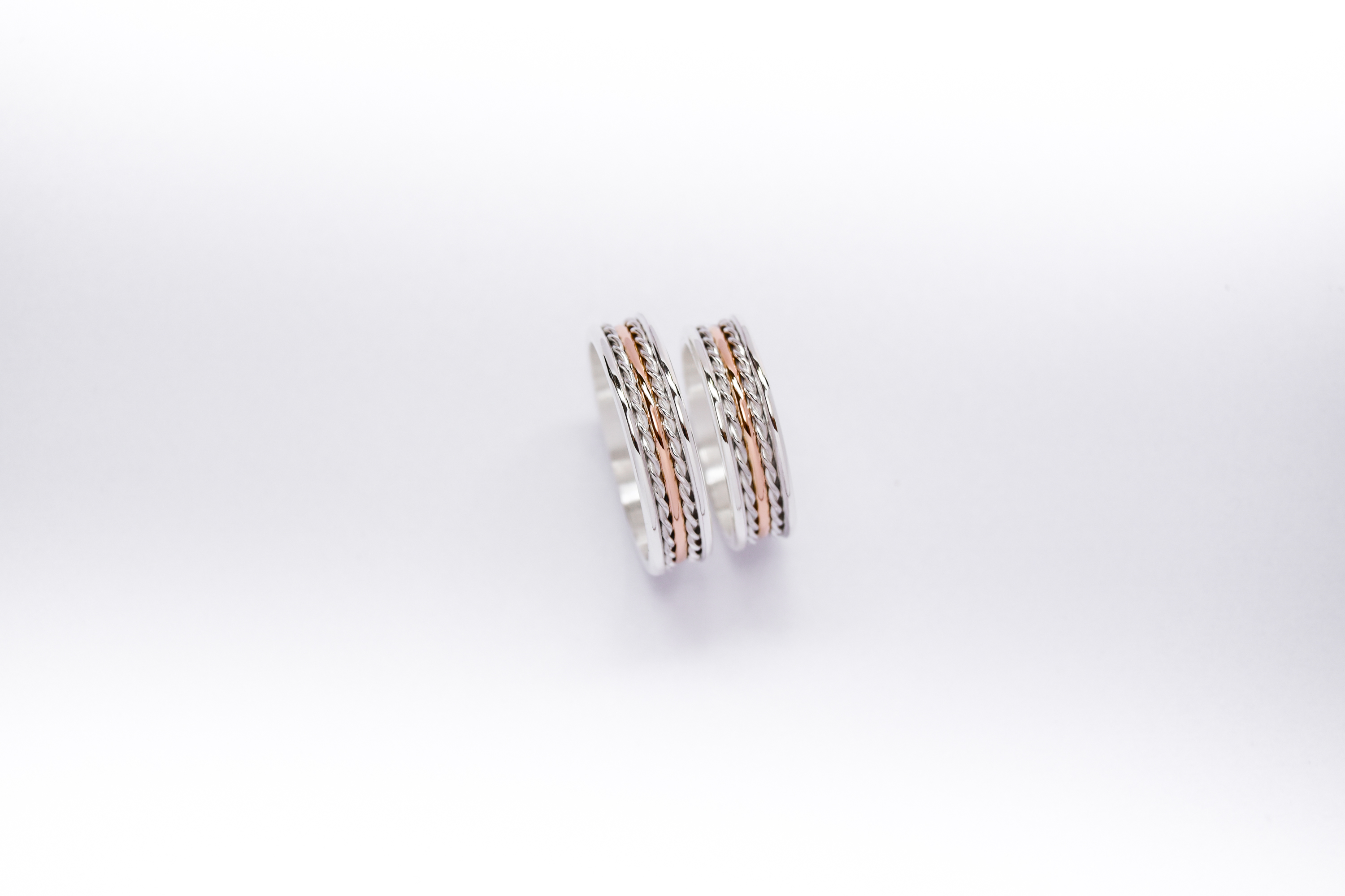 Alianzas de plata y oro 18k rosa con trenzas sobre fondo blanco