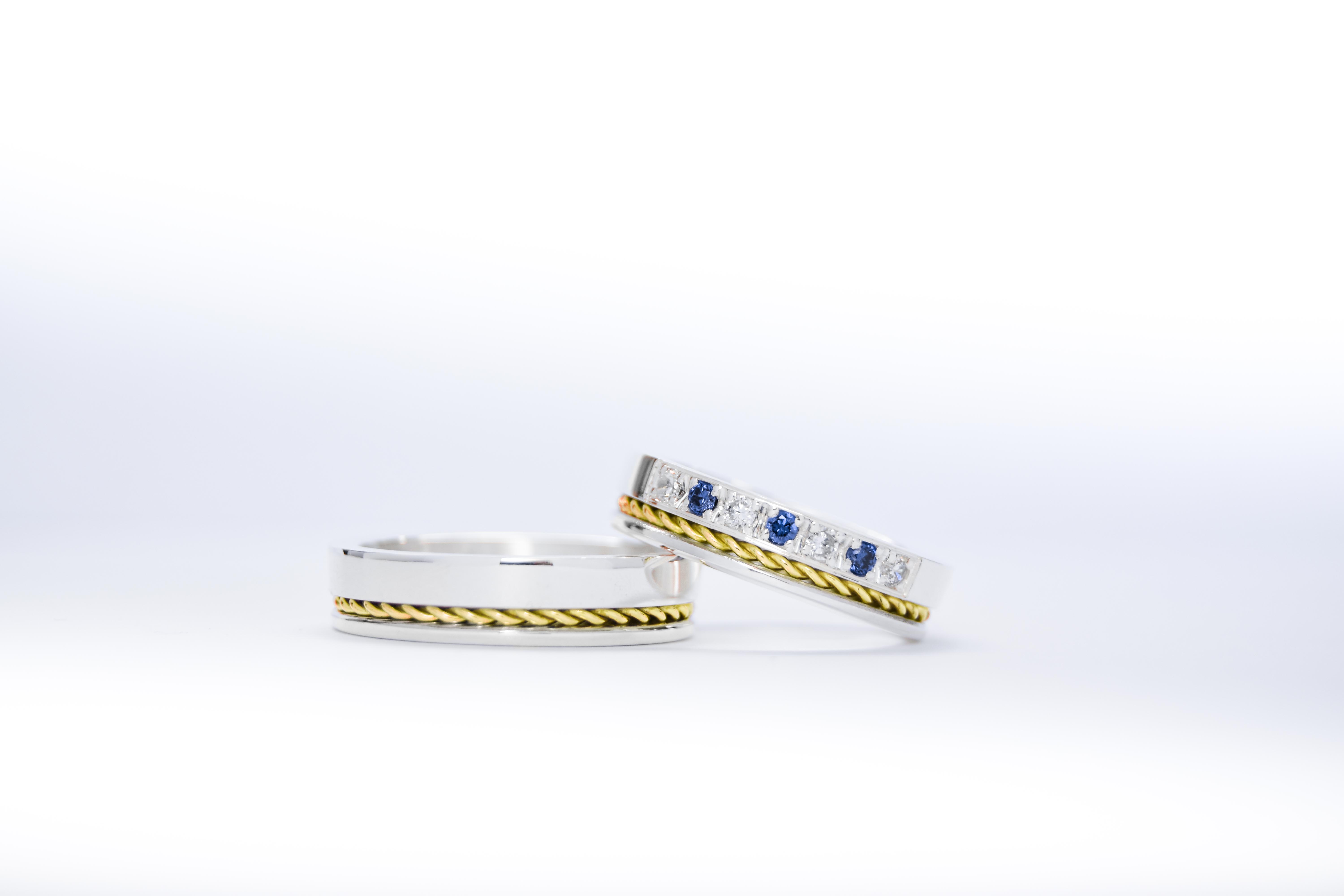 Alianzas de plata 950k y oro 18k amarillo con diamantes blancos y zafiros engarzadas. sobre fondo blanco.