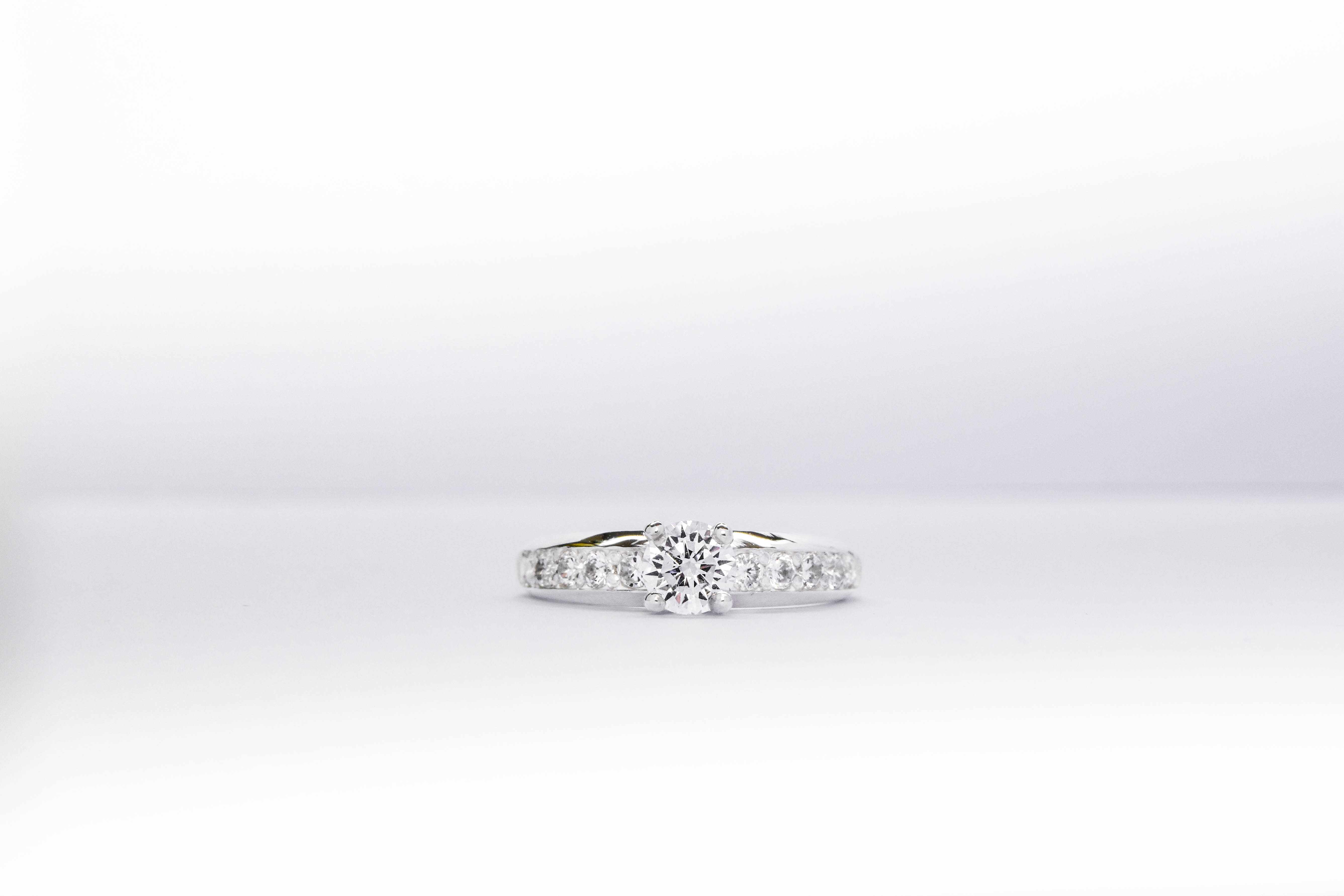 Anillo de compromiso de plata 925k con una gema blanca brillante y otras a los costados sobre fondo blanco