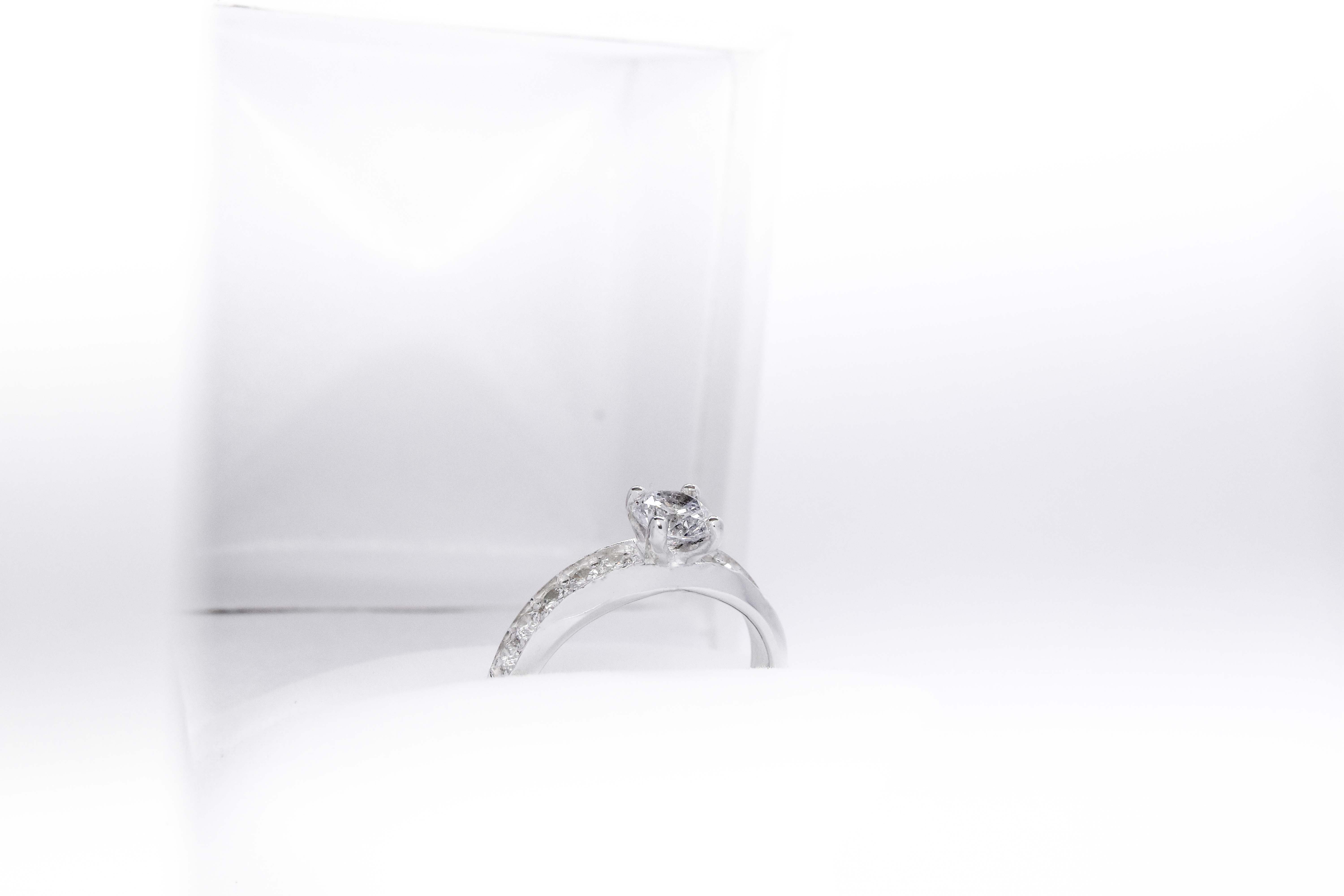 Anillo de compromiso de plata 925k con una gema blanca brillante y otras a los costados sobre fondo blanco