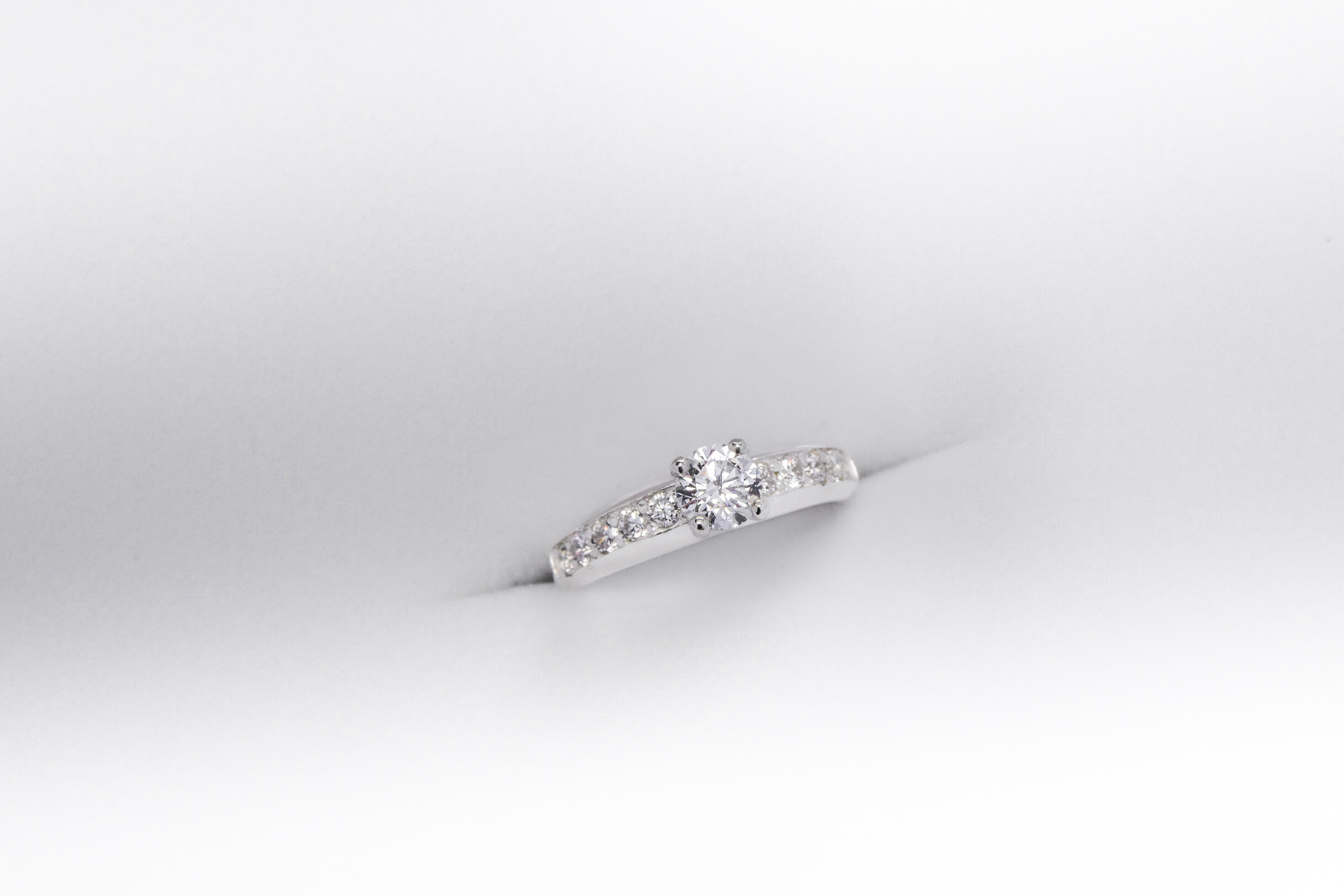 Anillo de compromiso de plata 925k con una gema blanca brillante y otras a los costados sobre fondo blanco