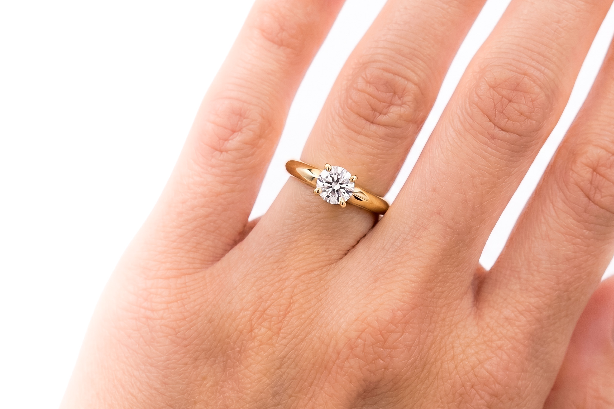 Anillo de compromiso oro 18K con un diamante talla brillante central en la mano de la modelo