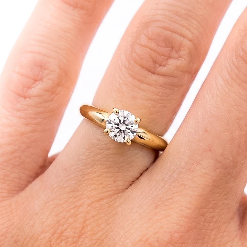 Anillo de compromiso oro 18K con un diamante talla brillante central en la mano de la modelo