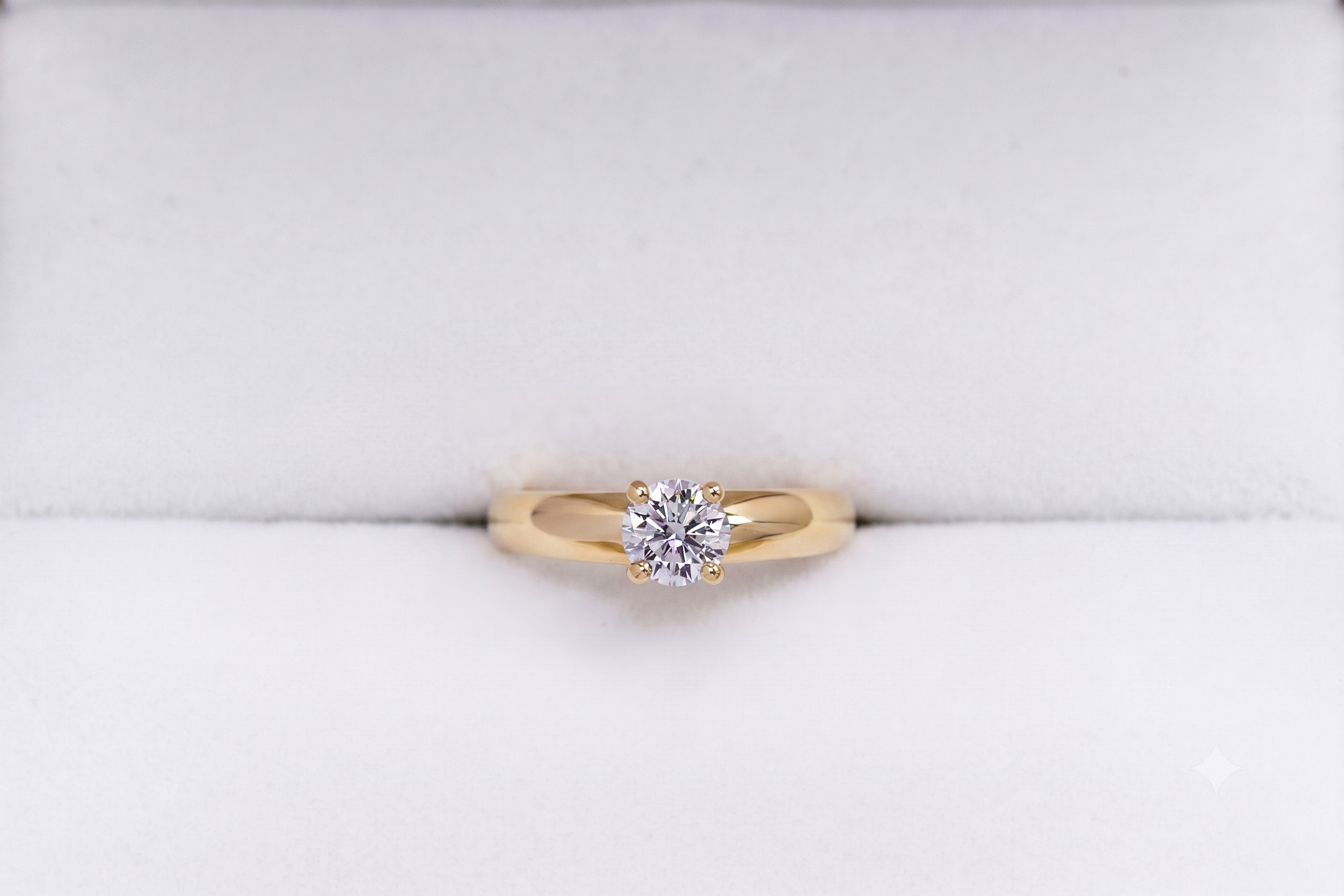 Anillo de compromiso oro 18K con un diamante talla brillante central sobre fondo blanco