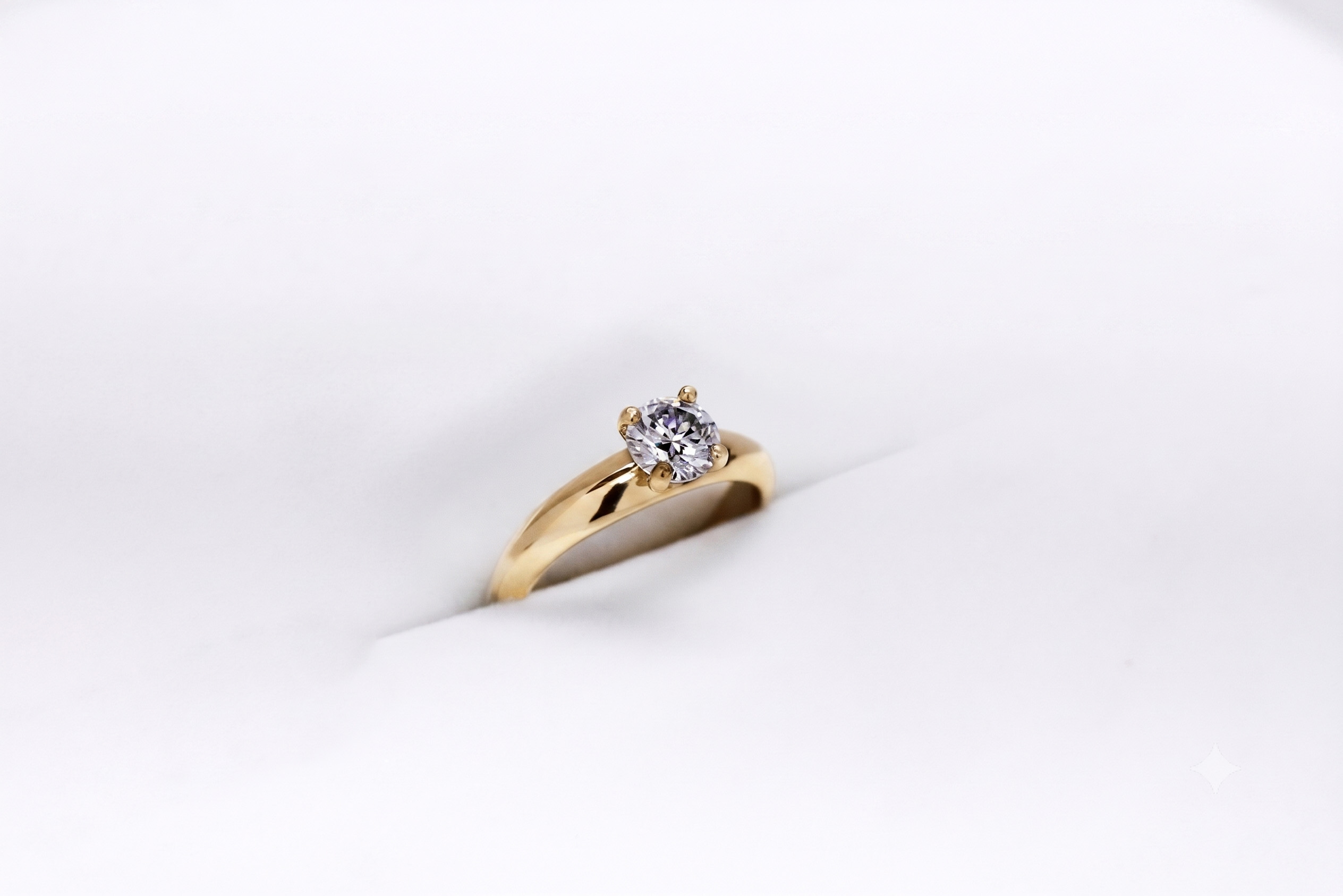 Anillo de compromiso oro 18K con un diamante talla brillante central sobre fondo blanco