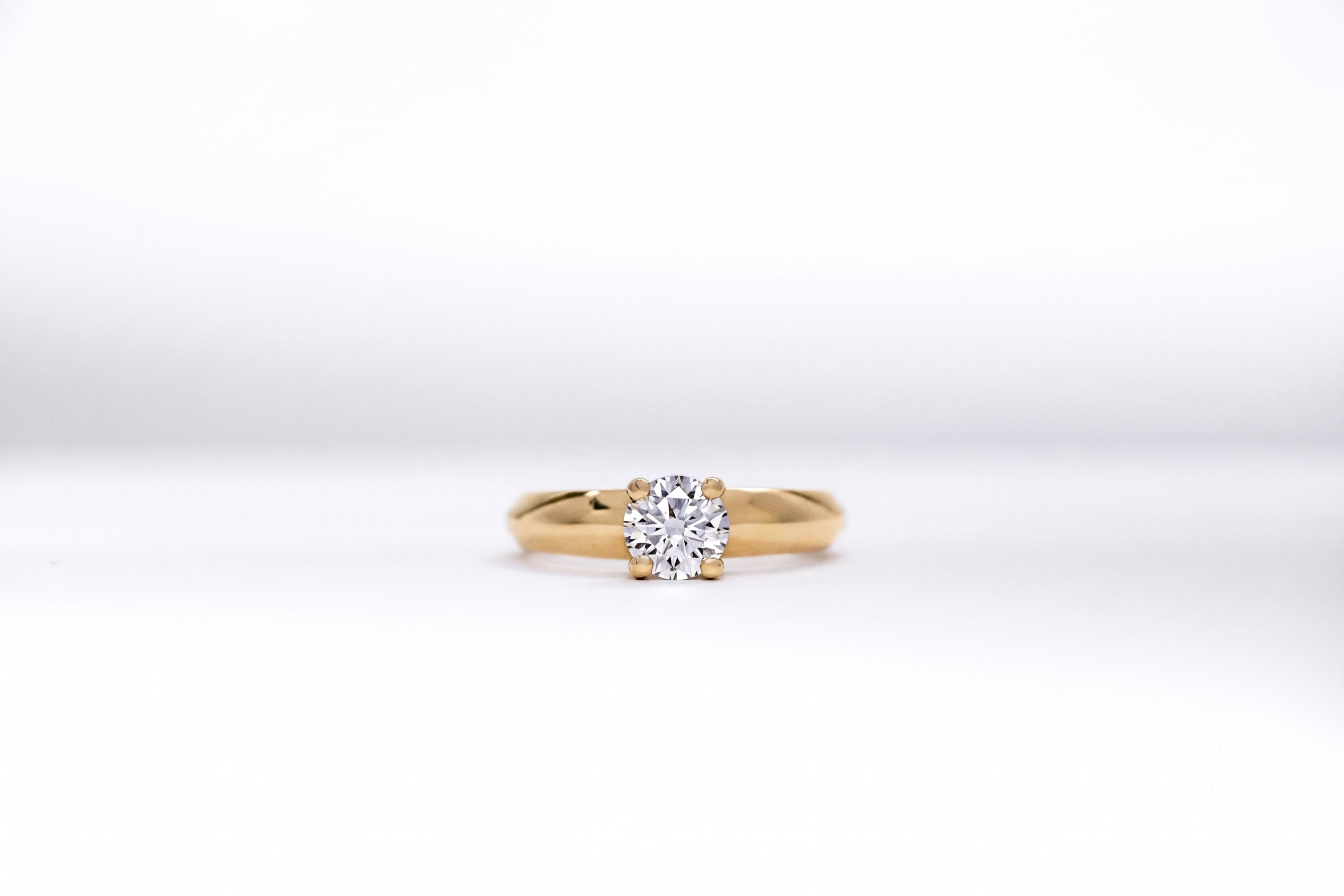 Anillo de compromiso oro 18K con un diamante talla brillante central sobre fondo blanco