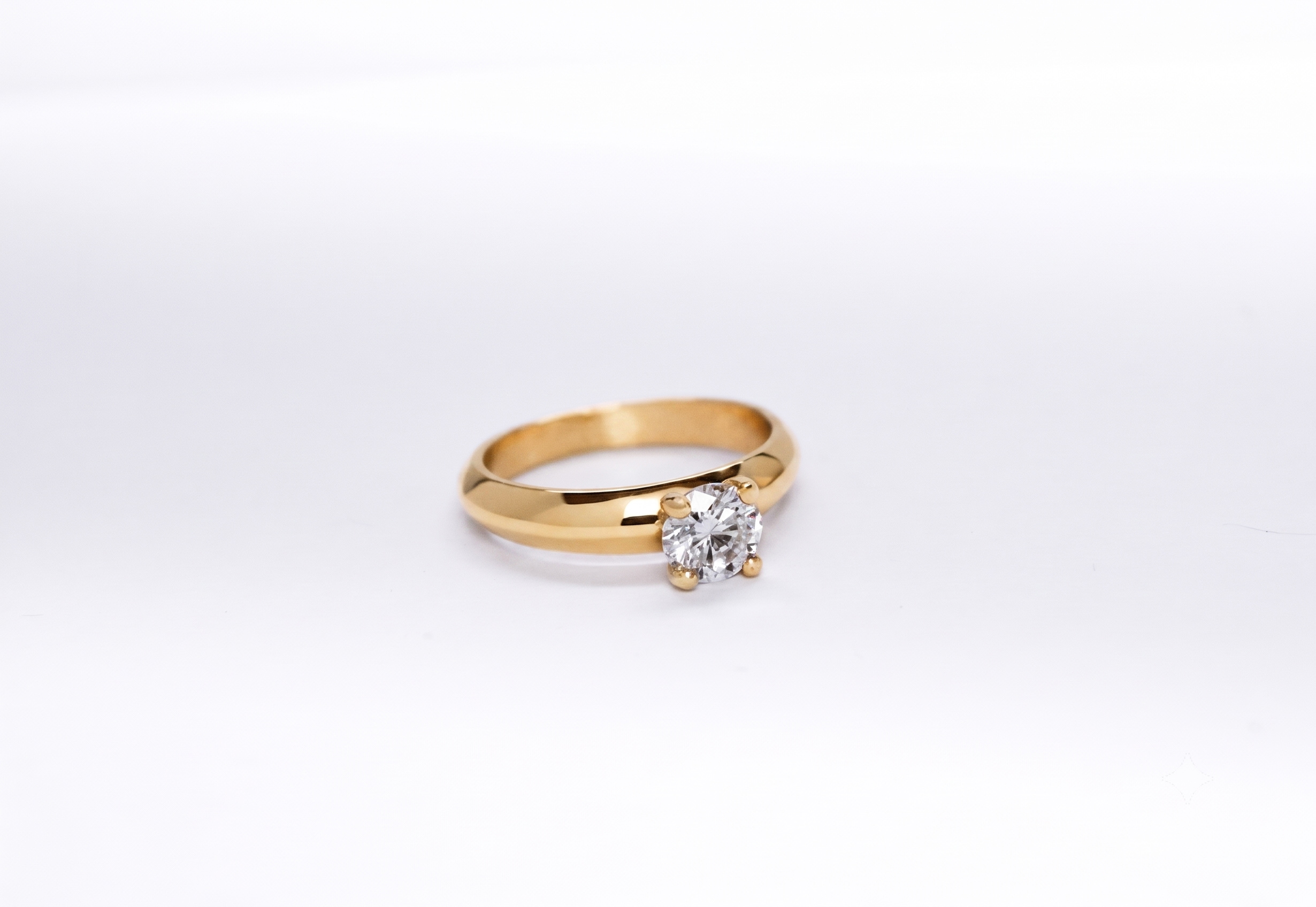Anillo de compromiso oro 18K con un diamante talla brillante central sobre fondo blanco