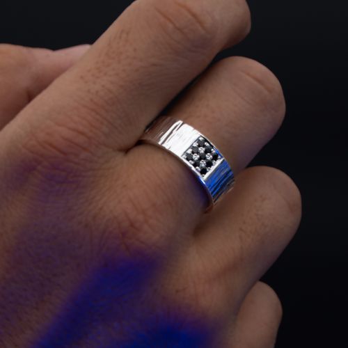Anillo de hombre de plata 999 en la mano con gemas negras sobre fondo negro