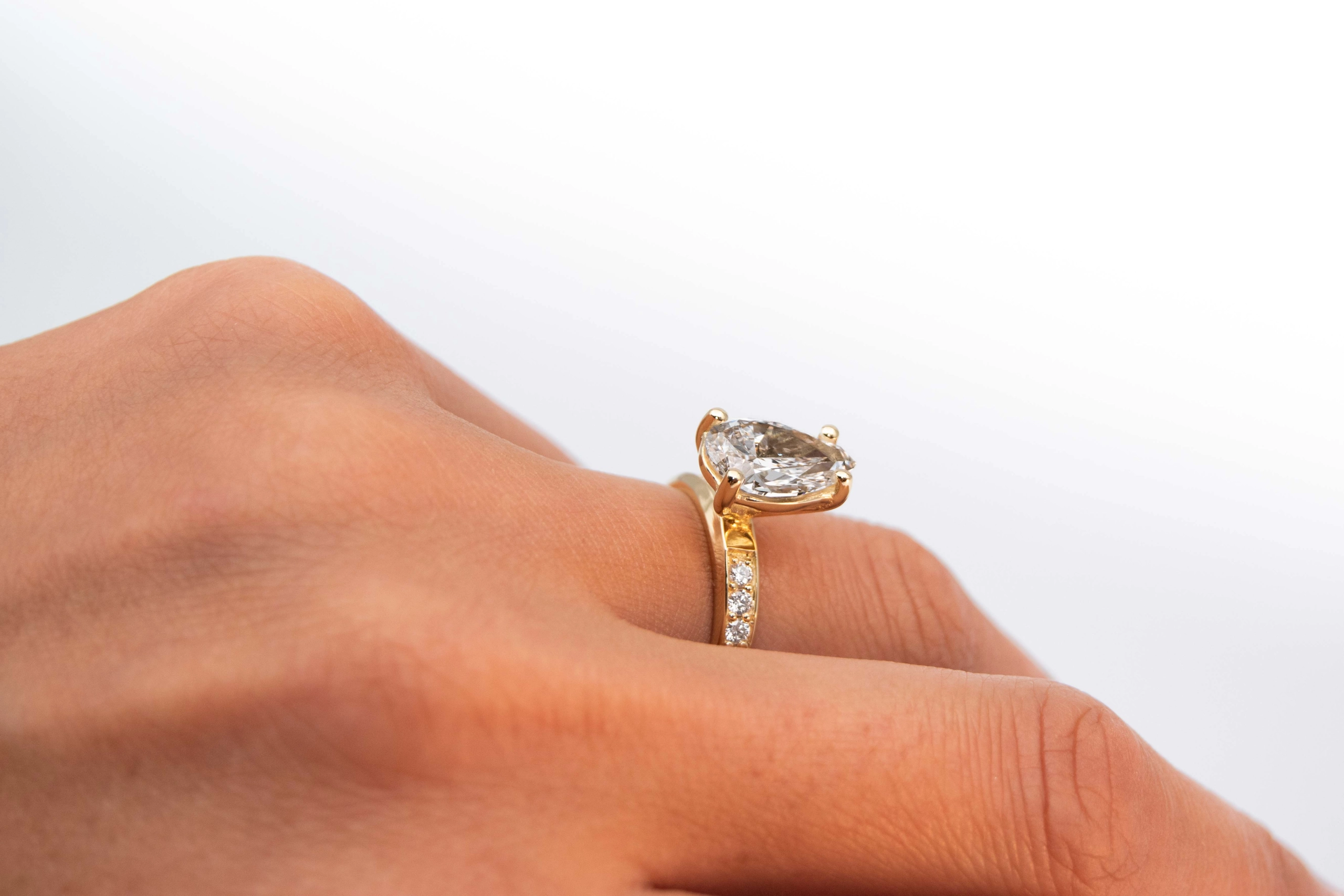 anillo de compromiso de oro modelo Taylor más con gema pear cut en la mano de la modelo