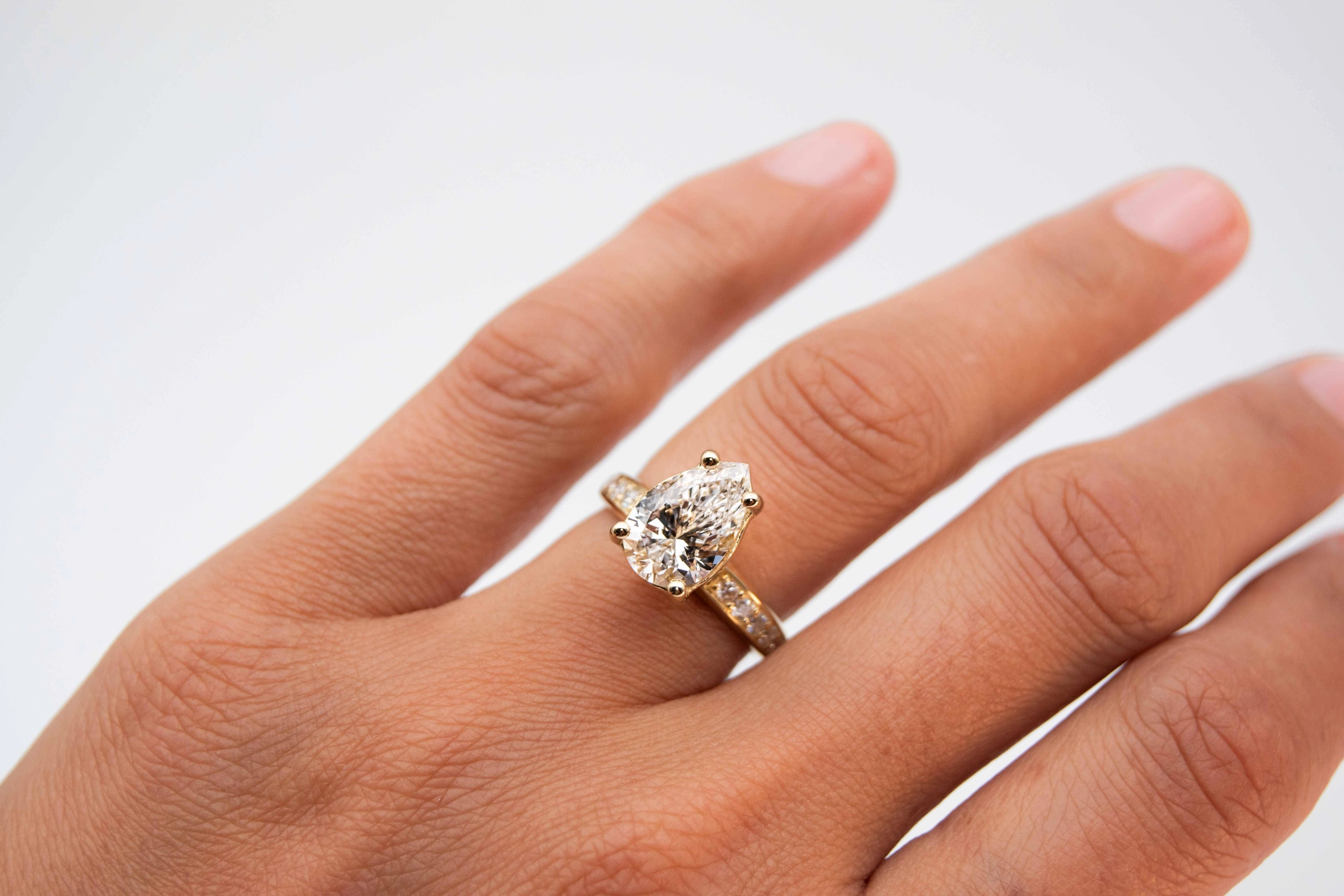 anillo de compromiso de oro modelo Taylor más con gema pear cut en la mano de la modelo